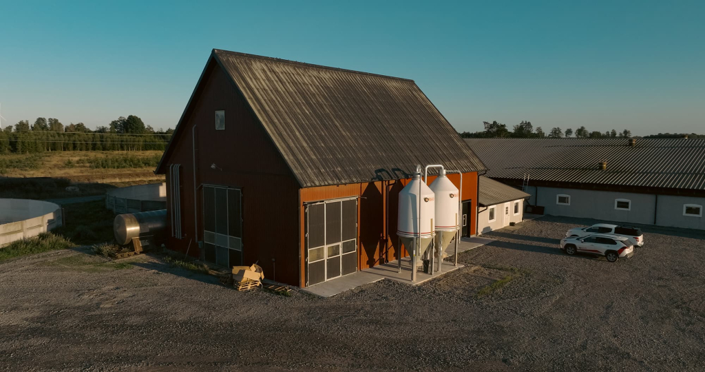 En lada med två silos. Det står två bilar bredvid