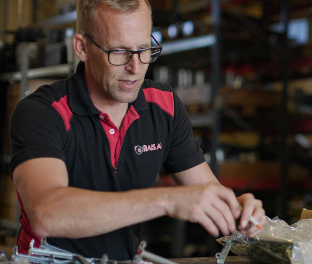 En man i Rais AB uniform monterar produkter i ett lager.