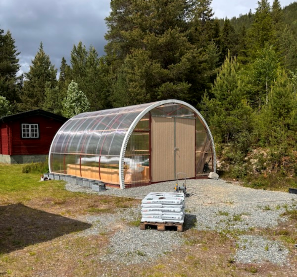 Växthus på tomt bredvid en skog