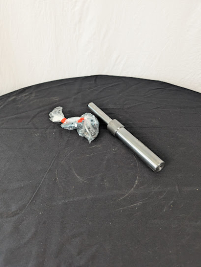 En drivaxel på ett svart bord framför en vit duk.