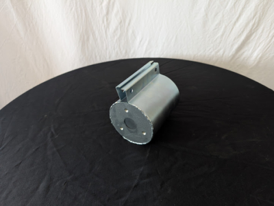 Anslutningsmanschett i metall på ett svart bord framför vit duk.